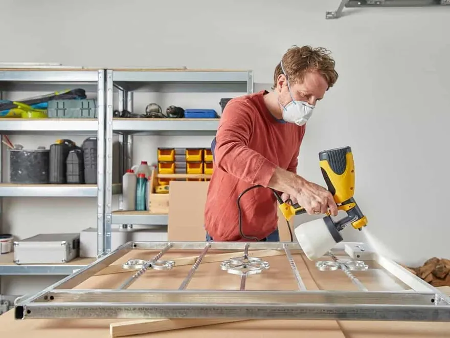 Using a spray gun to paint a metal frame