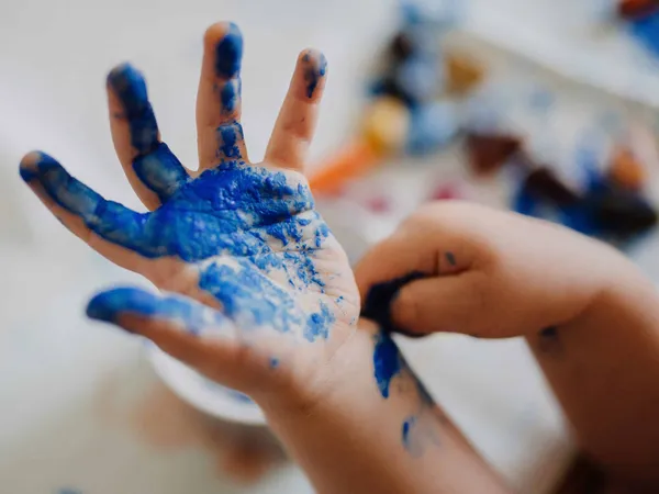 Children's hand covered in blue paint