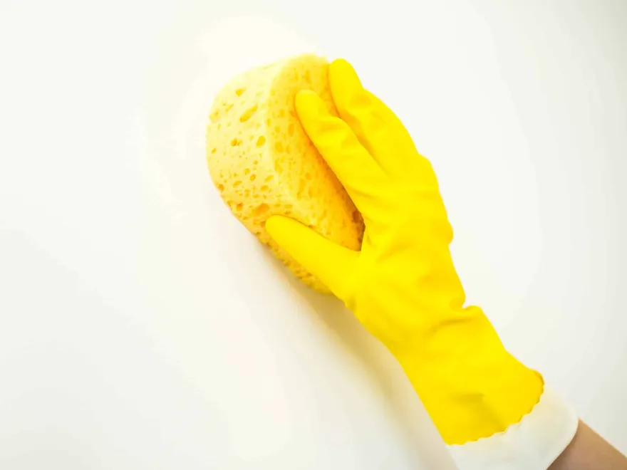 Washing wall with a sponge and wearing rubber glove